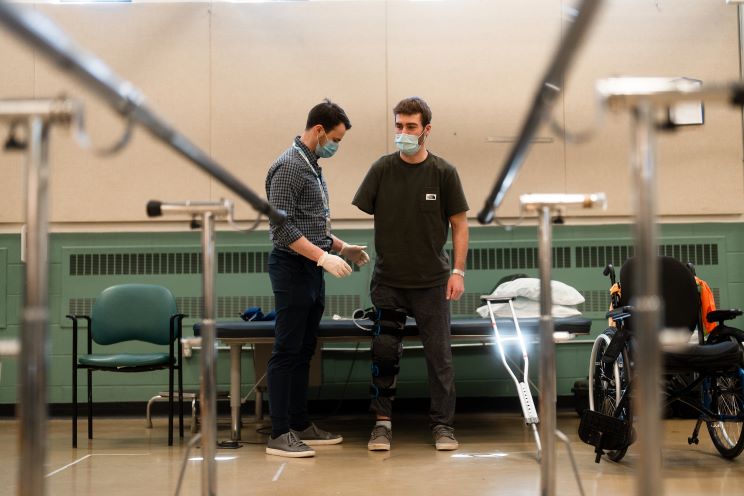 A patient and a healthcare worker working together in a physical rehabilitation setting. 