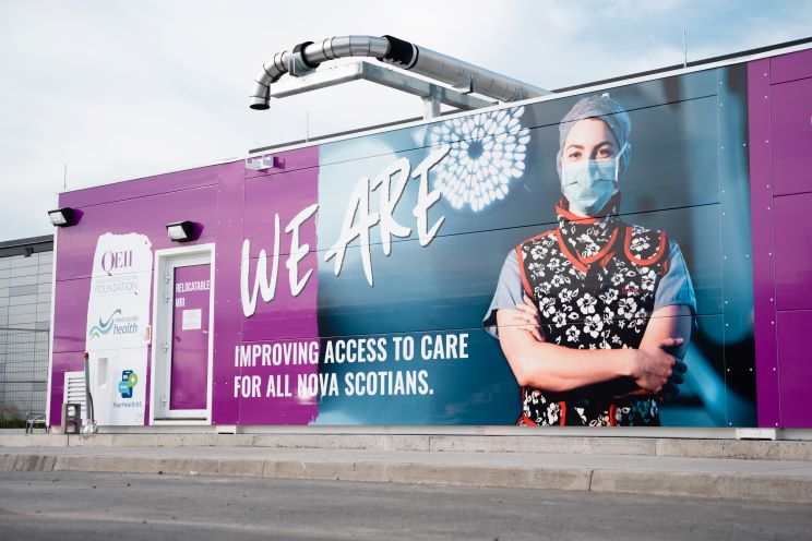 An industrial container is shown outside a health centre with a door that says Relocatable MRI, leading to an MRI inside the container. 