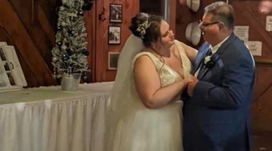 A female bride and her father embrace during a dance. 