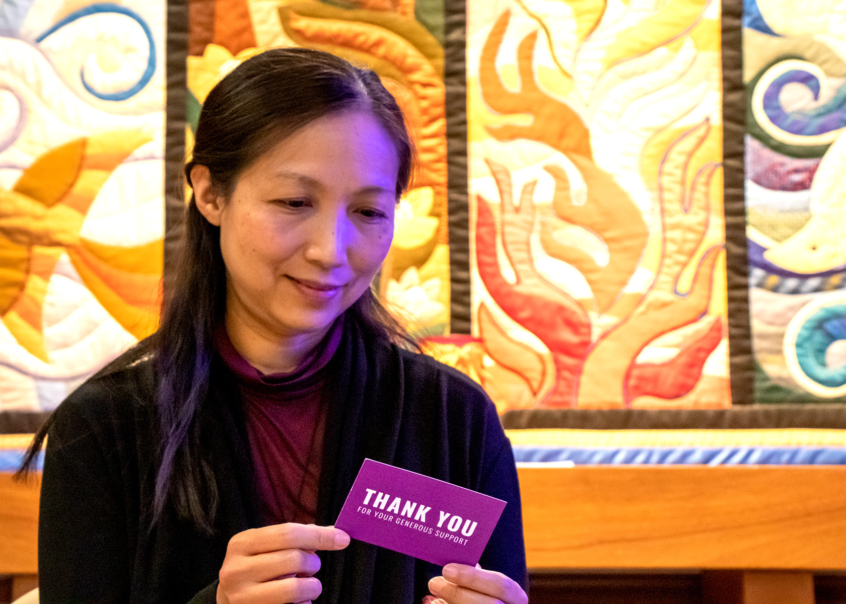 A woman holds a note in her hands and is reading the message. 