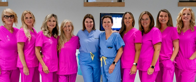 Women in scrubs, standing in front of robotics technology