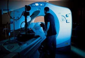Radiation therapist comforts a patient being scanned by the QEII's CT simulator machine, which resembles a CT scanner