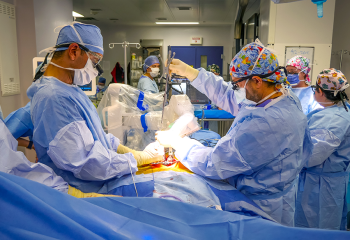 QEII surgeons performing a spinal robotics surgery, wearing blue scrubs.