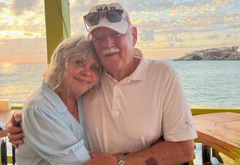 Couple hugging in front of water and warm sunset