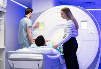 A patient prepares to have an MRI scan with the assistance of two medical professionals. 