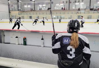 Shay with back facing camera, looking out at the ice rink