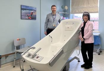 Two palliative care staff stand by the accessible whirlpool tub.