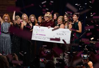 On-statge cheque presentation photo with confetti and celebrating more than $1.2M raised