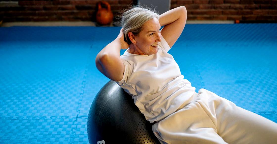 Woman in gym doing sit ups on a bosu ball