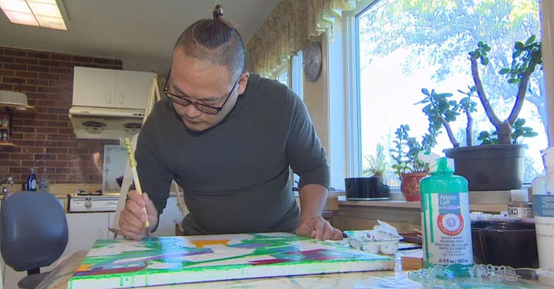 Artist Colin Chen paints a canvas in a studio