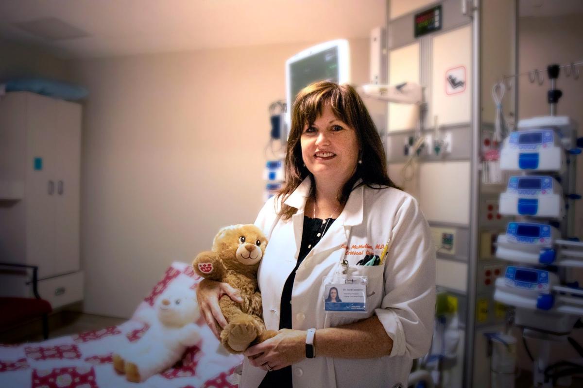 Dr. Sarah McMullin holds a donor-funded teddy bear provided through Teddy Bears with Heart