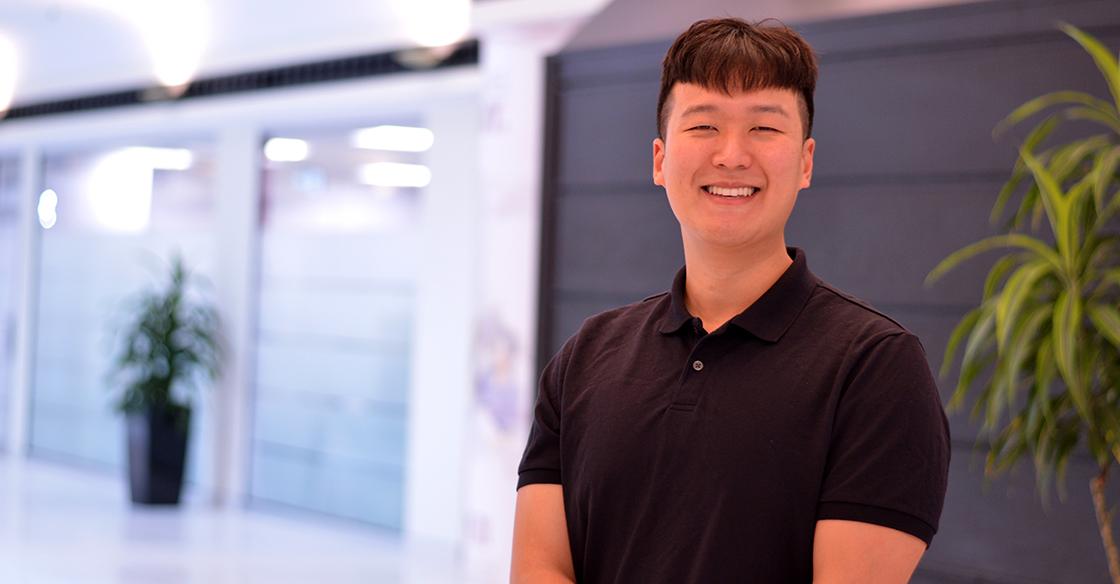 Sean Wang stands smiling, wearing a black t-shirt
