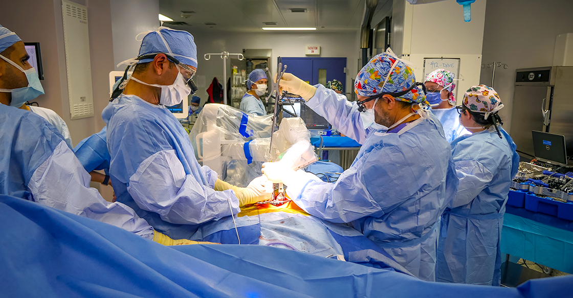 QEII surgeons performing a spinal robotics surgery, wearing blue scrubs.