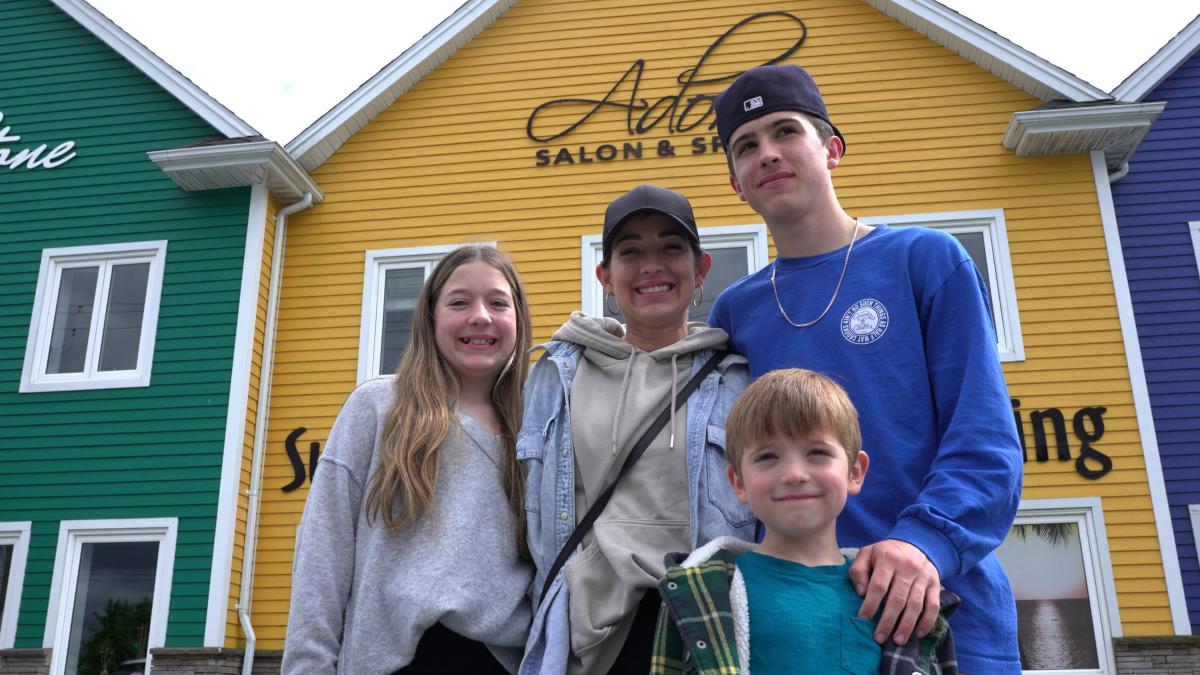 A woman and three children smile at the camera with brightly coloured buildings behind them. 