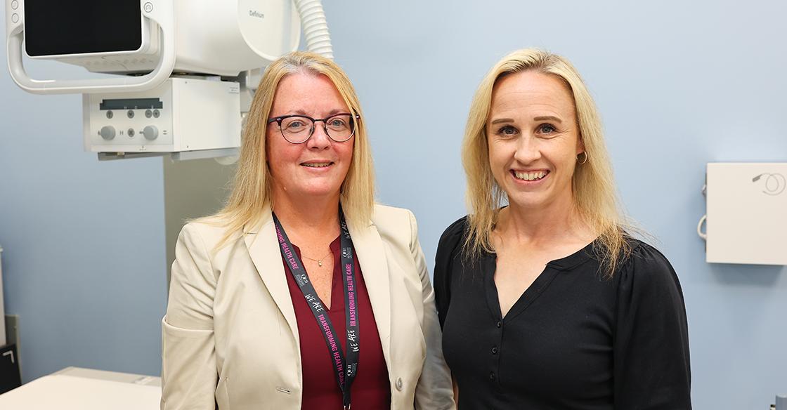 Two women stand in front of the  newly acquired Precision 180 Fluoroscopy Unit at the QEII’s Rehab Centre. 