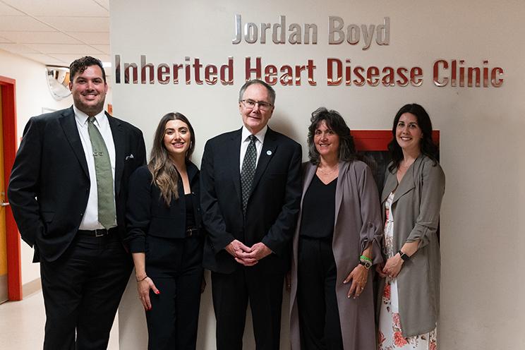 The Boyd family stands under the sign at the QEII's Jordan Boyd Inherited Heart Disease Clinic.