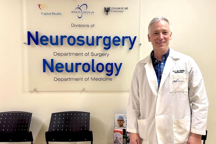 Dr. Lutz Weise stands in front of the neurosurgery sign at the QEII.