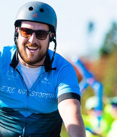 Ride for Cancer participant rides through and finish line and pumps his fist