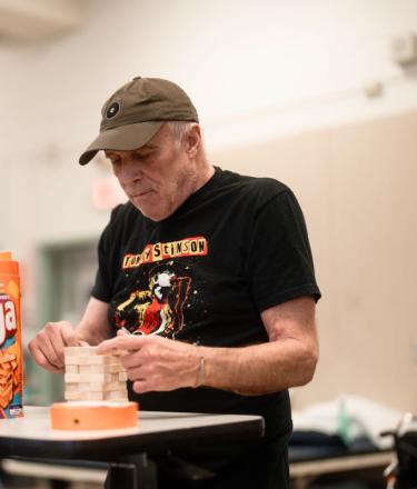 A man plays Jenga in a physical rehabilitation centre under guidance of a female therapist. 