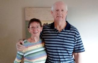 Older couple stands in front of beige wall and painting