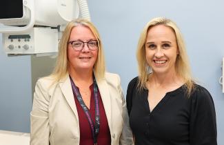 Two women stand in front of the  newly acquired Precision 180 Fluoroscopy Unit at the QEII’s Rehab Centre. 