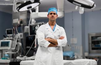 Dr Ribeiro standing in OR, with arms crossed and smiling