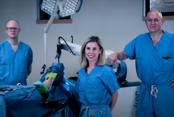 Dr. Glen Richardson, Janie Wilson, PhD and Dr. Michael Dunbar stand with the orthopaedic surgical robot.