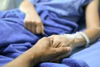 two patients holding hands on a hospital bed