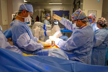 Surgeons performing a spinal procedure in a QEII operating room, using robotics technology