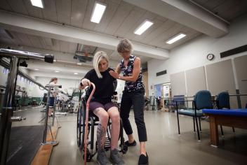 A woman in a wheelchair receives support from a physical therapist. 